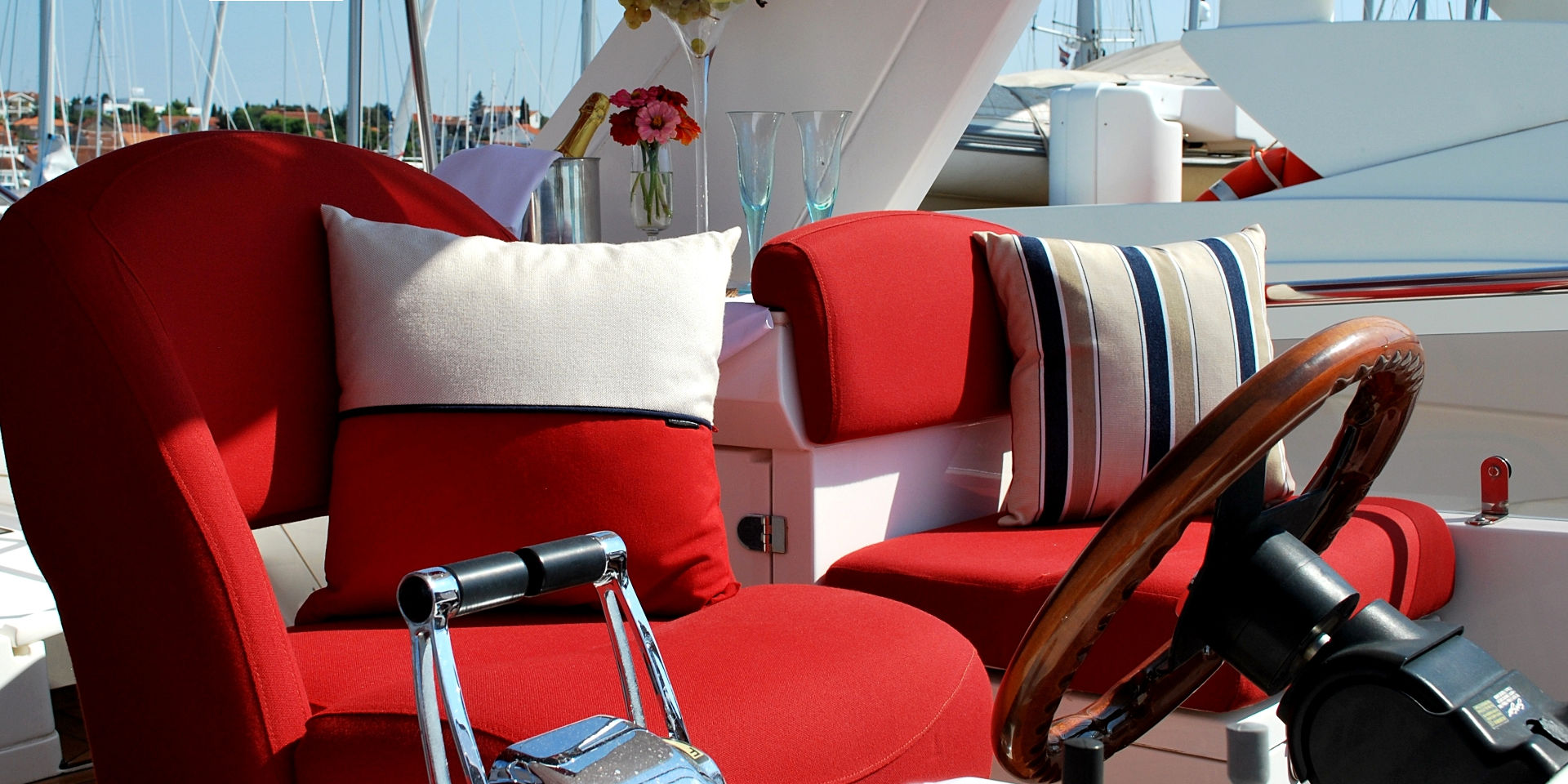 Sealine T-60 yacht exterior, newly reupholstered helm seats in bold red colour with complimentary Frey luxury pillows in striped fabric.