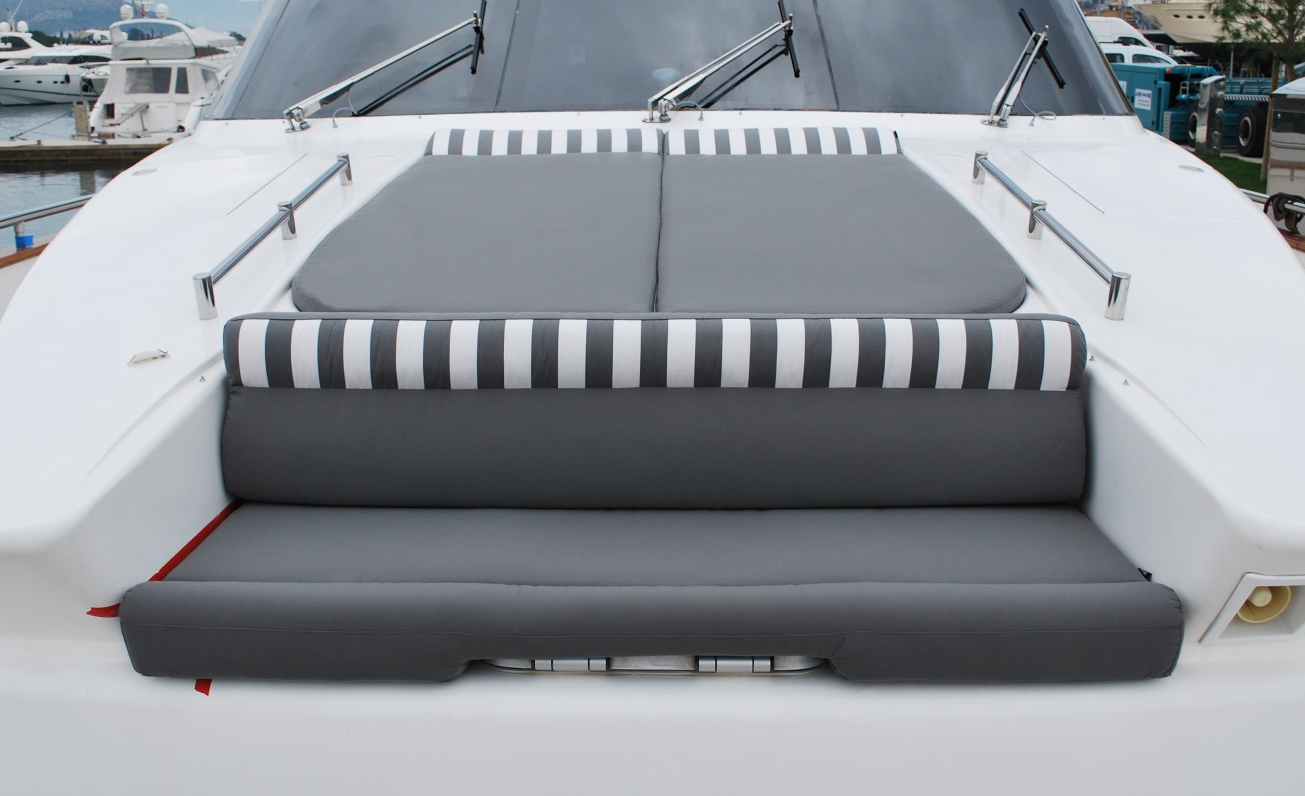 A dynamic look by separating sunbathing area from front seats on bow deck with cushions in charcoal grey and striped edging.