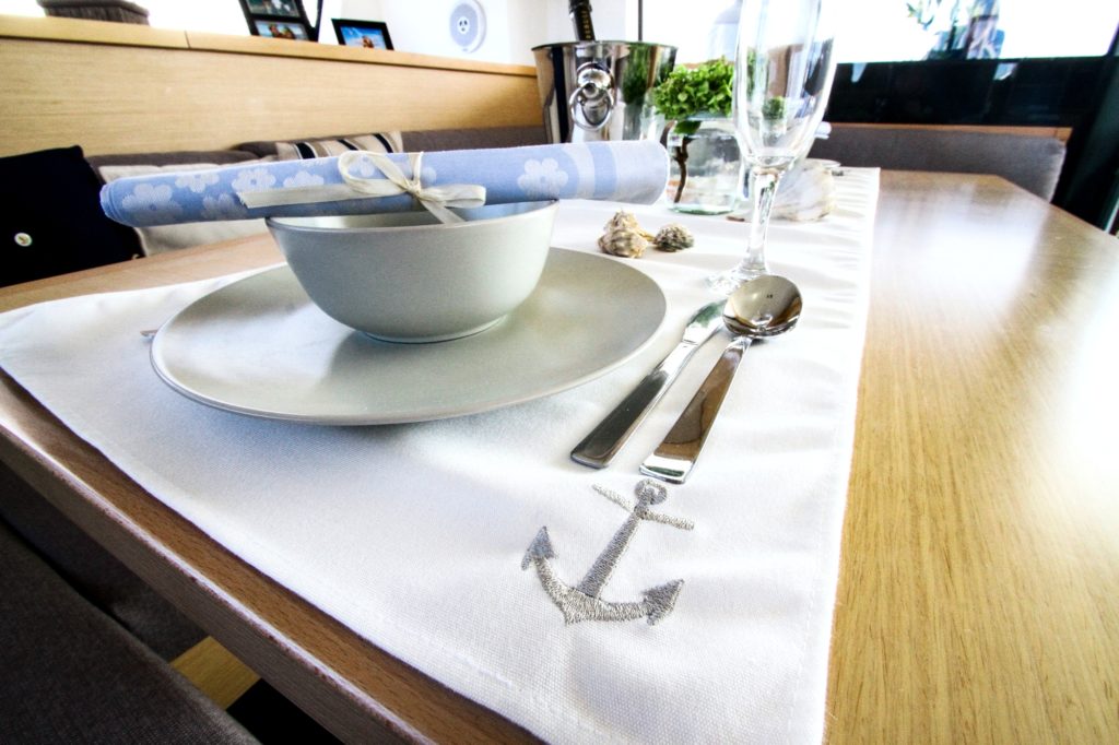 Distinctive Frey tableware. Customised tablecloth with embroidered silver anchor & matching napkins add a graceful touch.