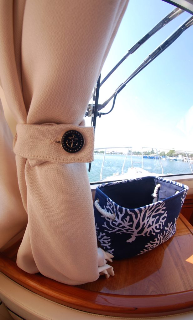 Stylish ivory interior yacht curtains with nautical button tieback, beautifully offset polished teak wood elements on yacht.