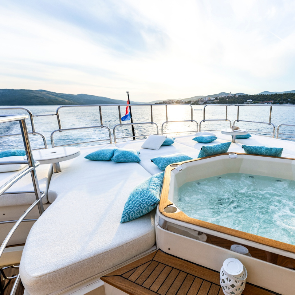 Sunseeker 34 yacht exterior refit white boucle cushion sundeck sunbed by jacuzzi with Frey geometric turquoise luxury pillows.